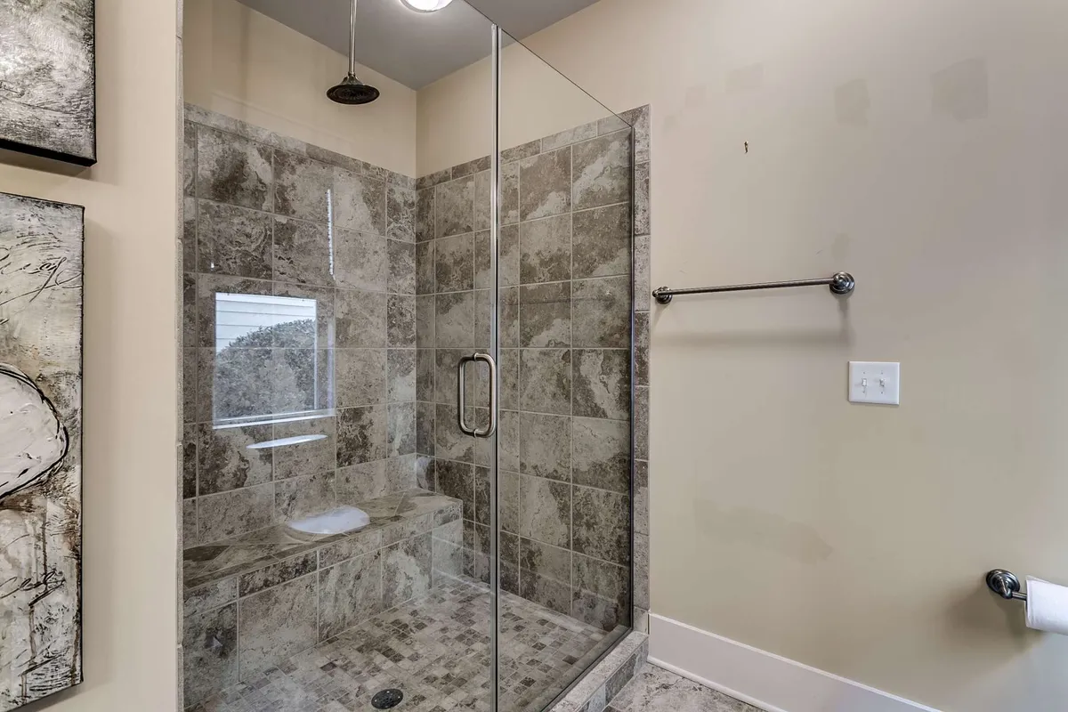 A sleek and modern interior spa-style bathroom with a glass shower enclosure, textured tile walls, and upscale fixtures, evoking a calm and rejuvenating mood for moments of self-care and relaxation.