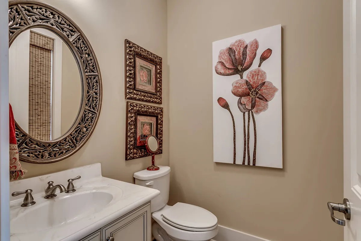 A serene and elegant bathroom space with a large decorative mirror, floral artwork, an ornate framed picture, and a vanity with sink. The mood is peaceful, offering a moment for self-care and relaxation.